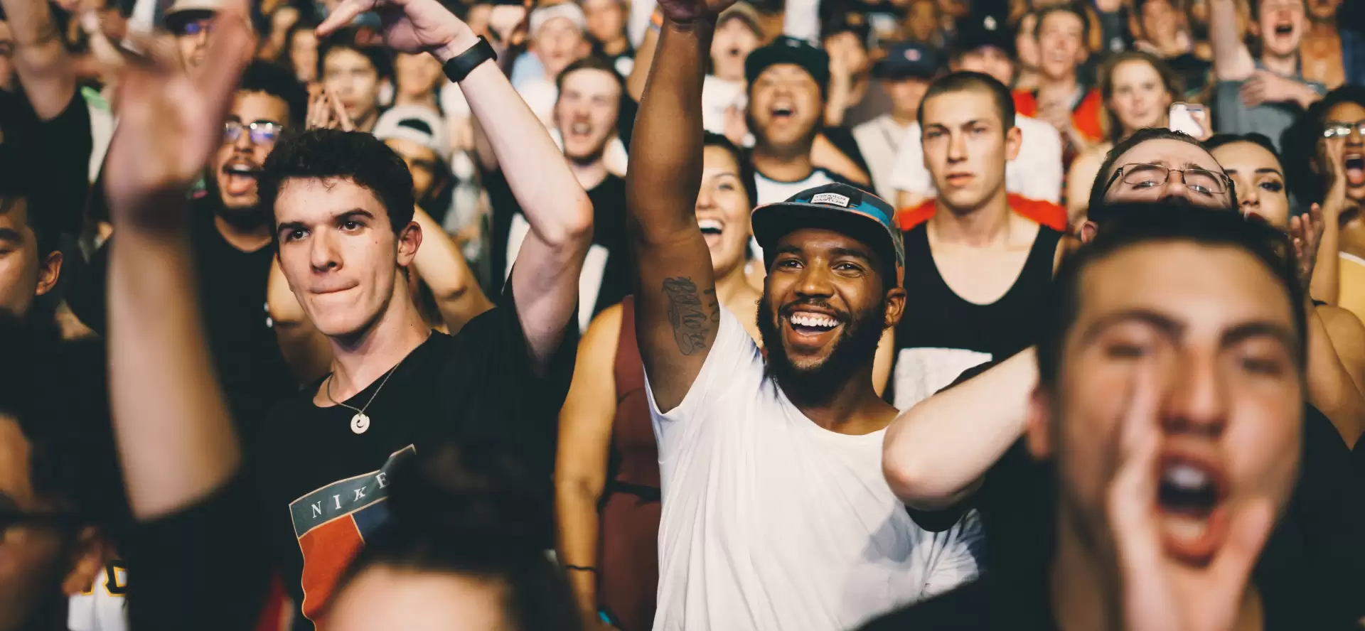 Foule de jeunes gens souriants et levant les bras lors d'un concert